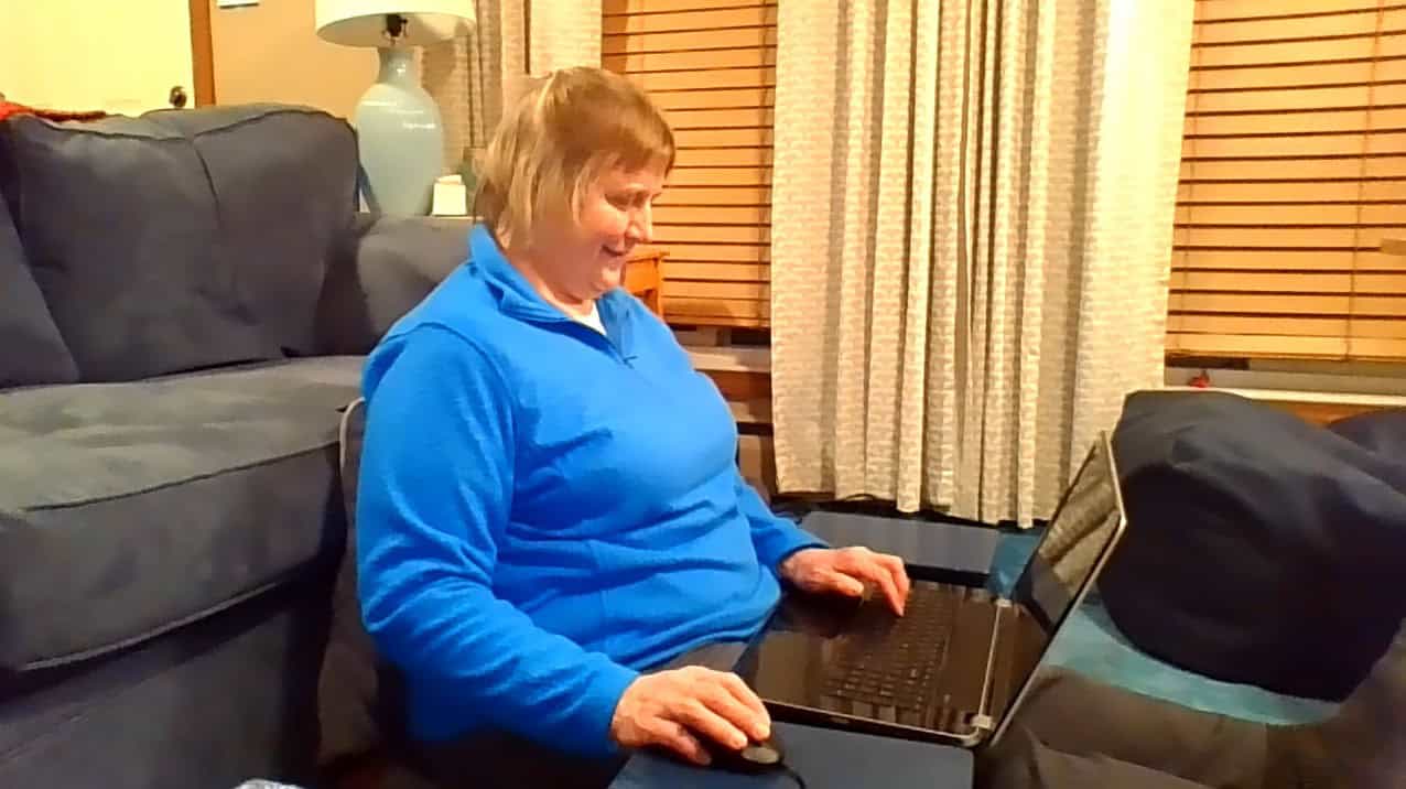 Woman working on laptop at home, focusing on hand health and ergonomics.