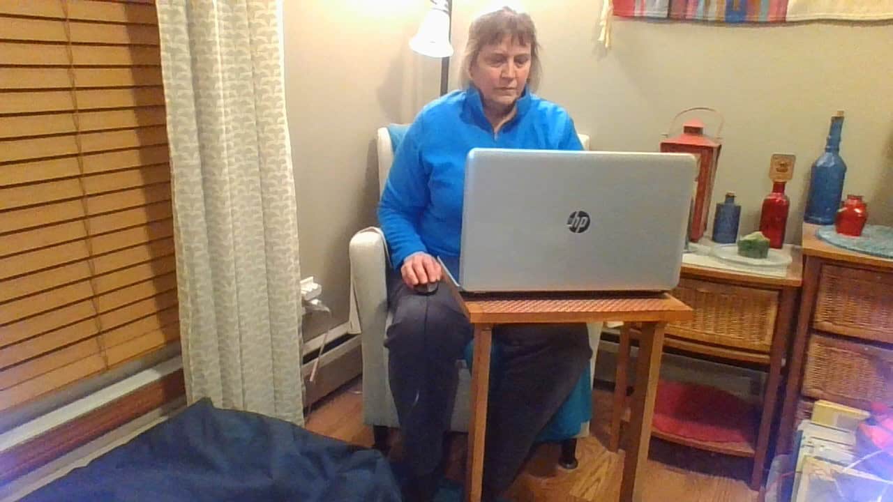 Woman working on laptop at home, focusing on hand health and ergonomics.