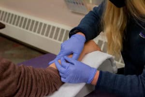 Hand therapy session at Alaska Hand Rehab with a therapist wearing gloves.